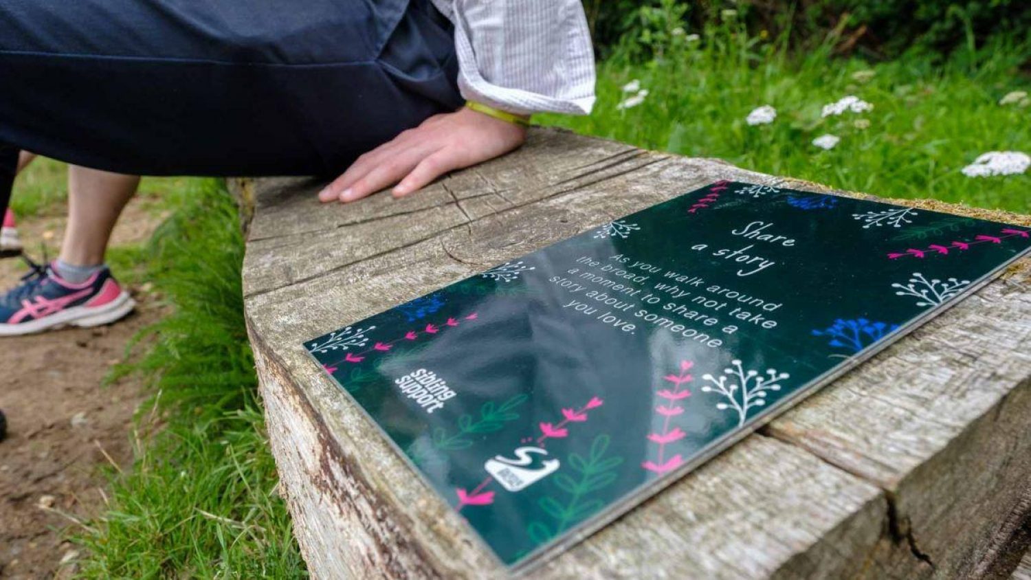 Sibling Support mindfulness walk, young person's hand on bench next to Sibling Support plaque