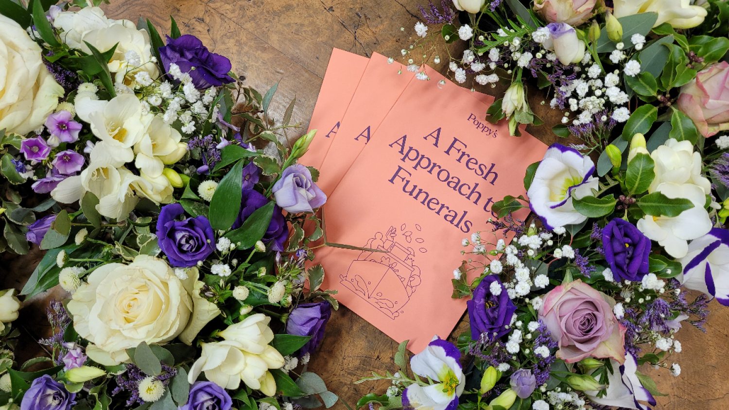 Purple and white funeral flowers, with Poppy's booklet in centre