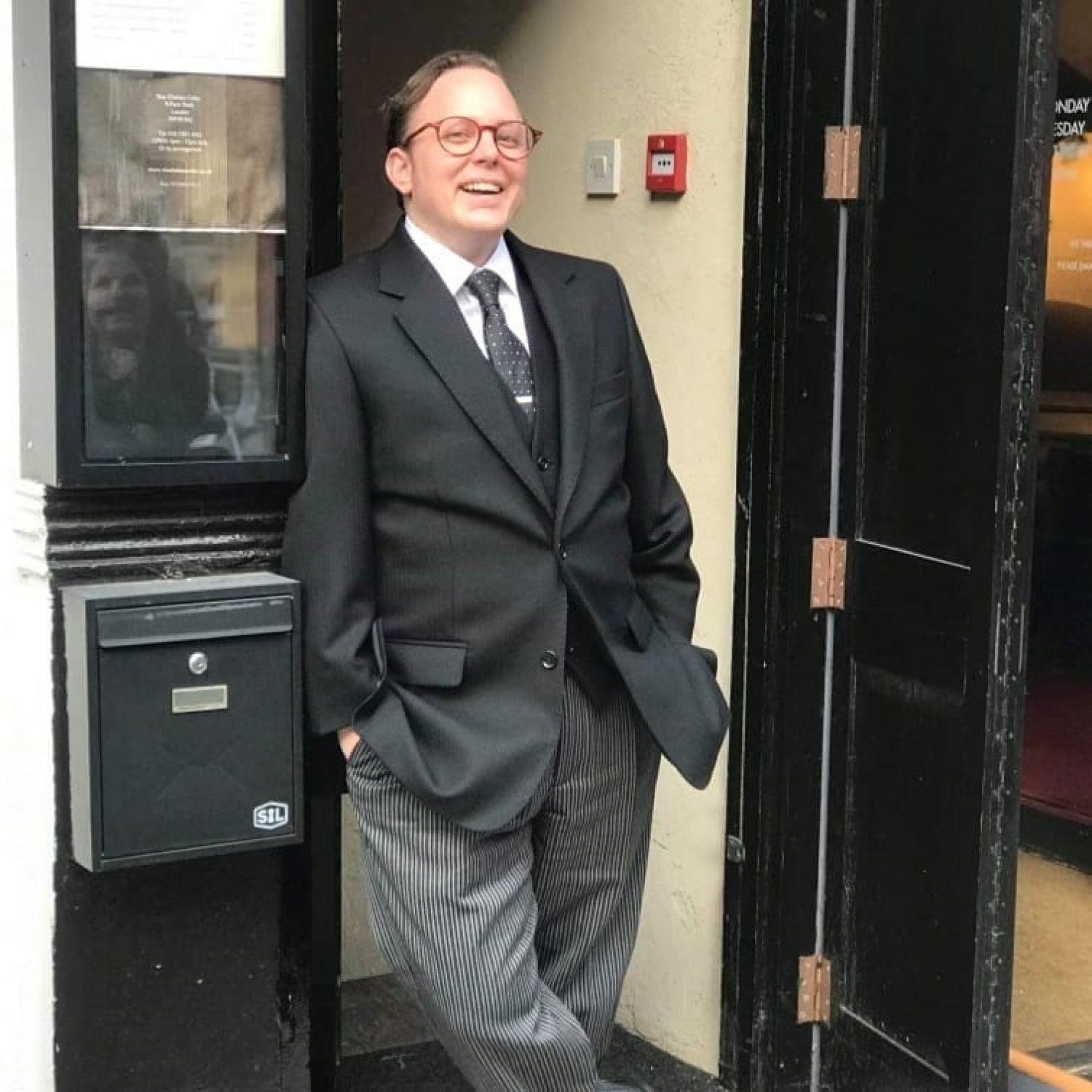 Funeral director Ash Hayhurst in suit by door