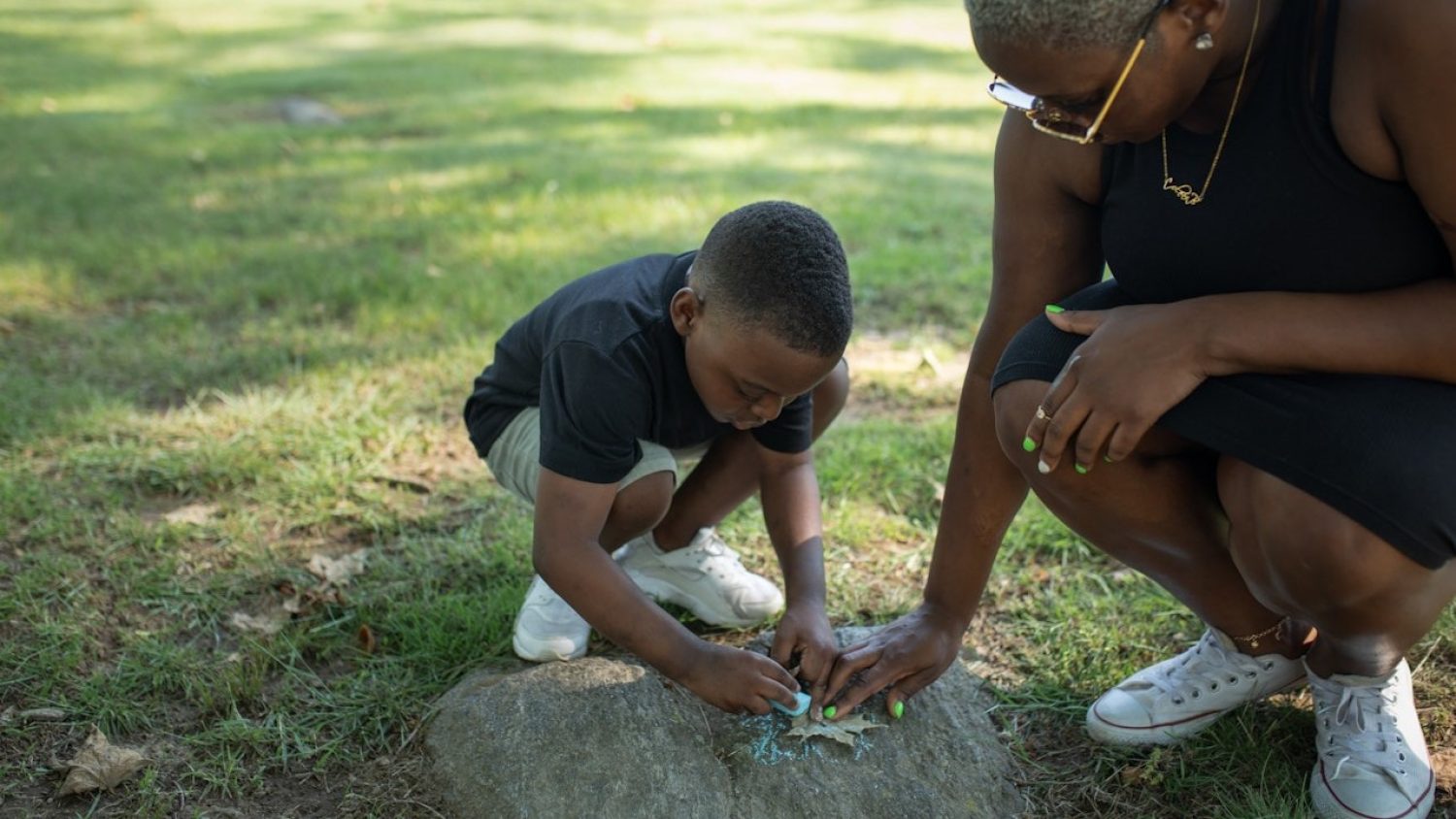 Adult and child looking at a fallen leaf in countryside