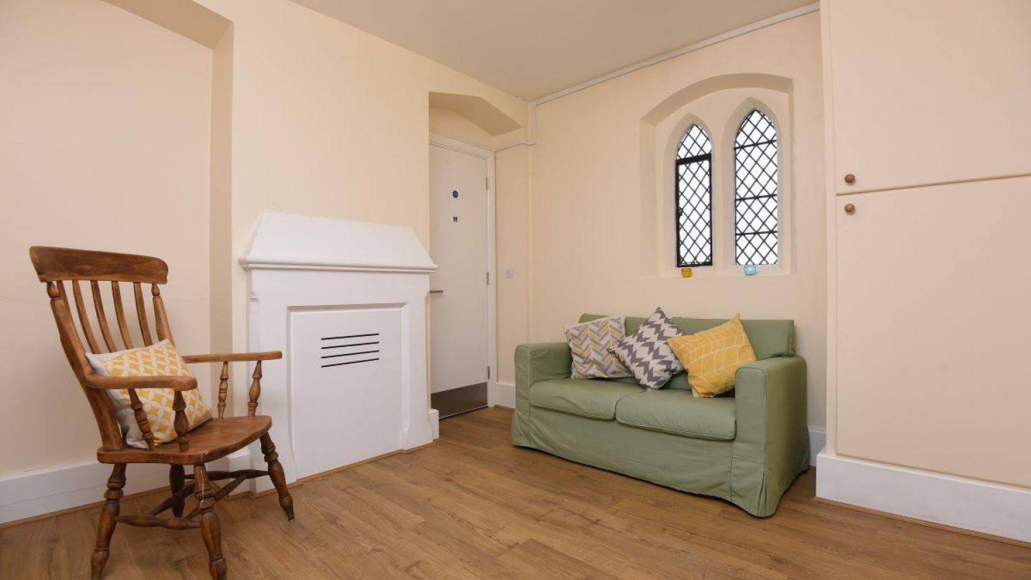 Friends and family room at Poppy's, London funeral director, showing green sofa, chair and light painted walls and wooden floor