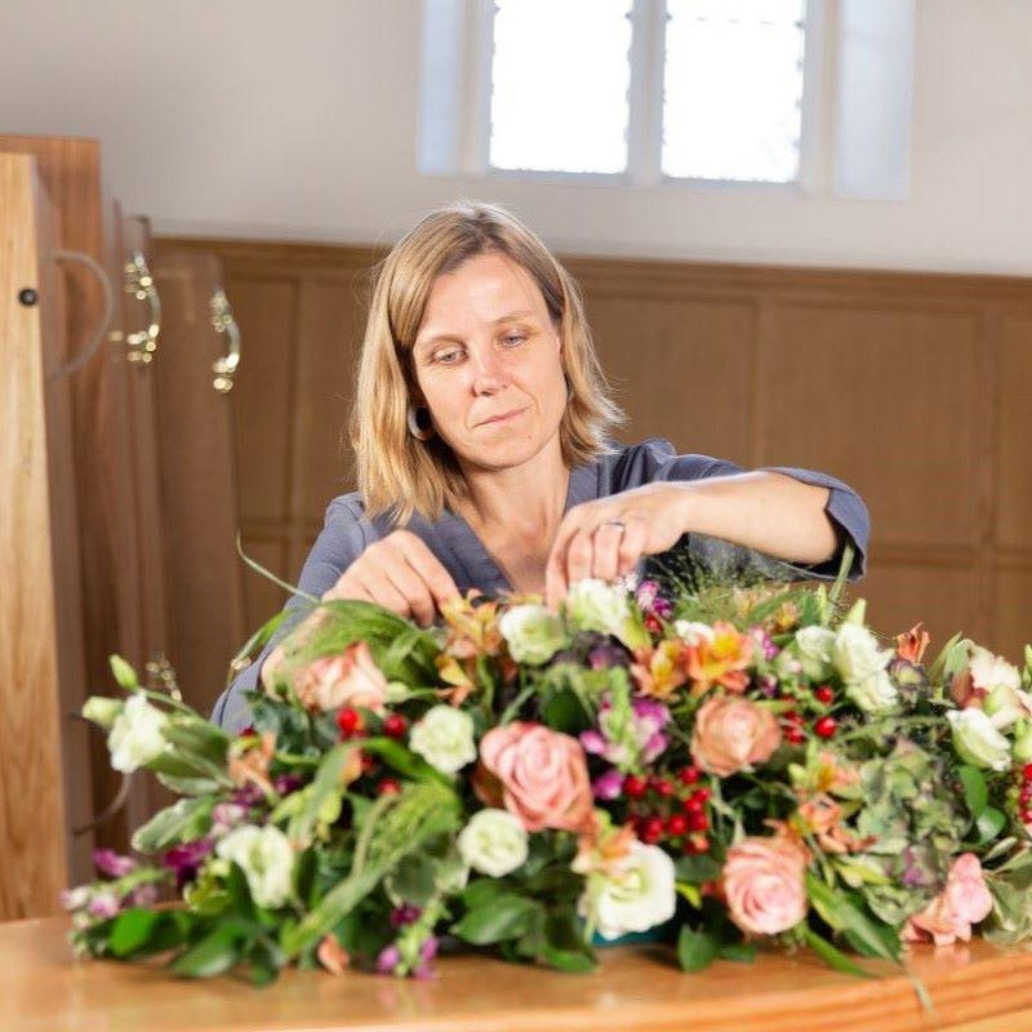 Poppy's funeral director Hannah arranging flowers on a coffin