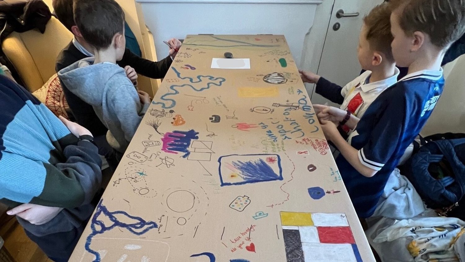 Cardboard coffin with children writing messages and drawings on it.