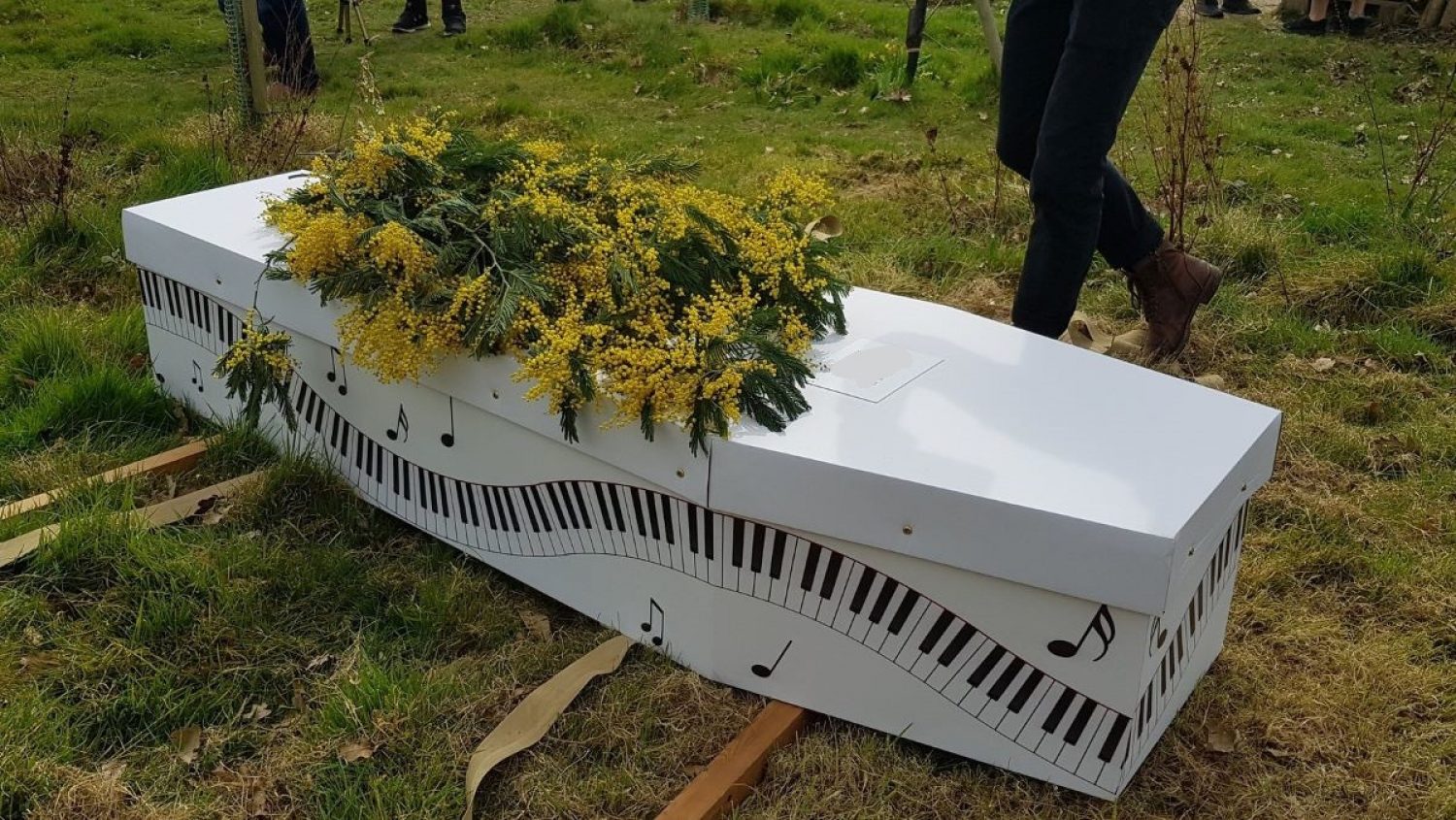 Cardboard coffin in white, printed with piano keys design