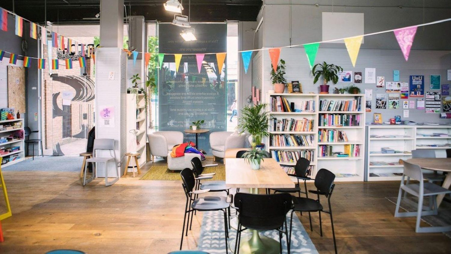 London LGBTQ+ centre room, with bookshelves, rainbow bunting and cafe-style tables and chairs