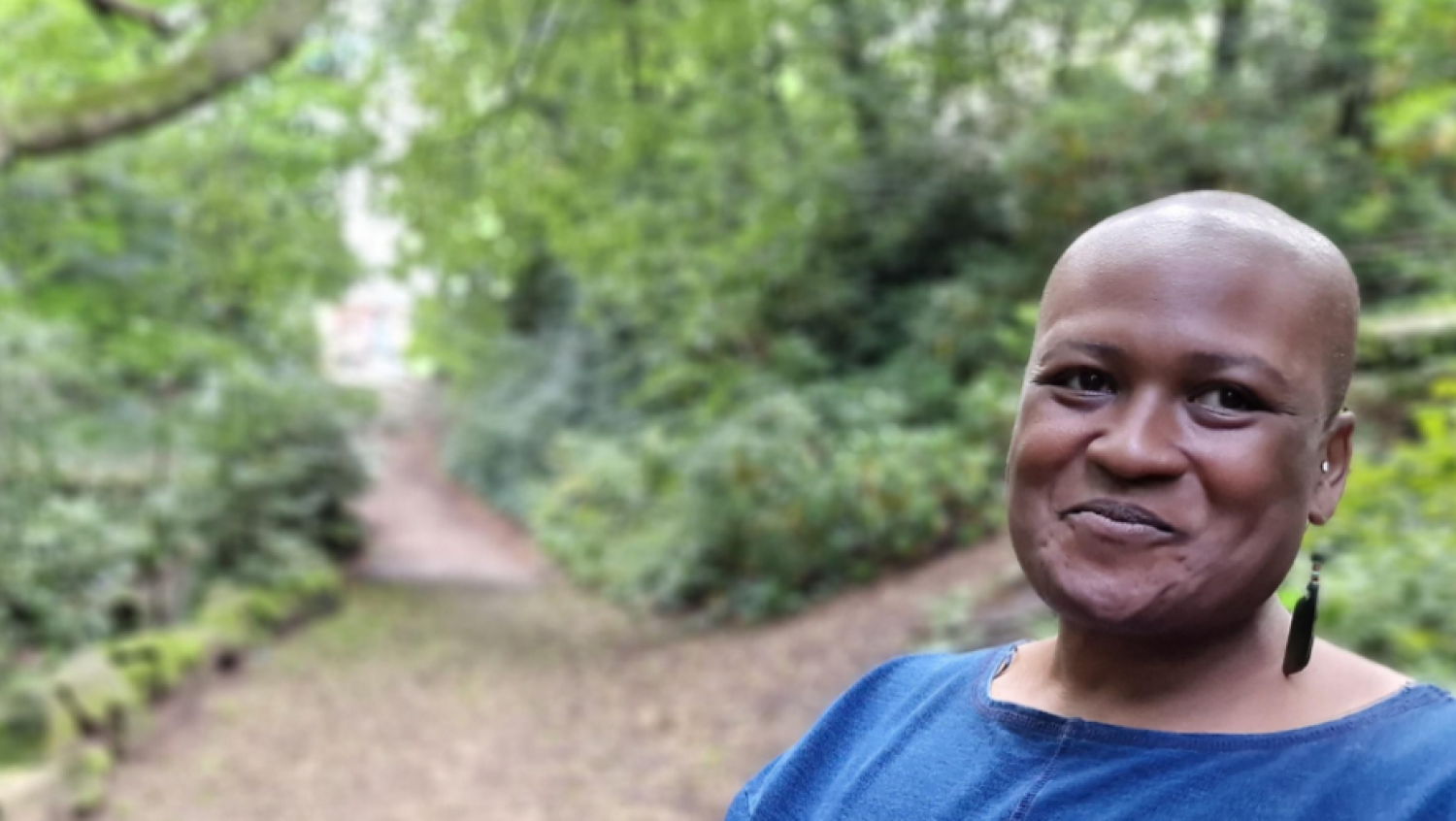 Laura D Pusey, funeral celebrant in woodland with path behind her