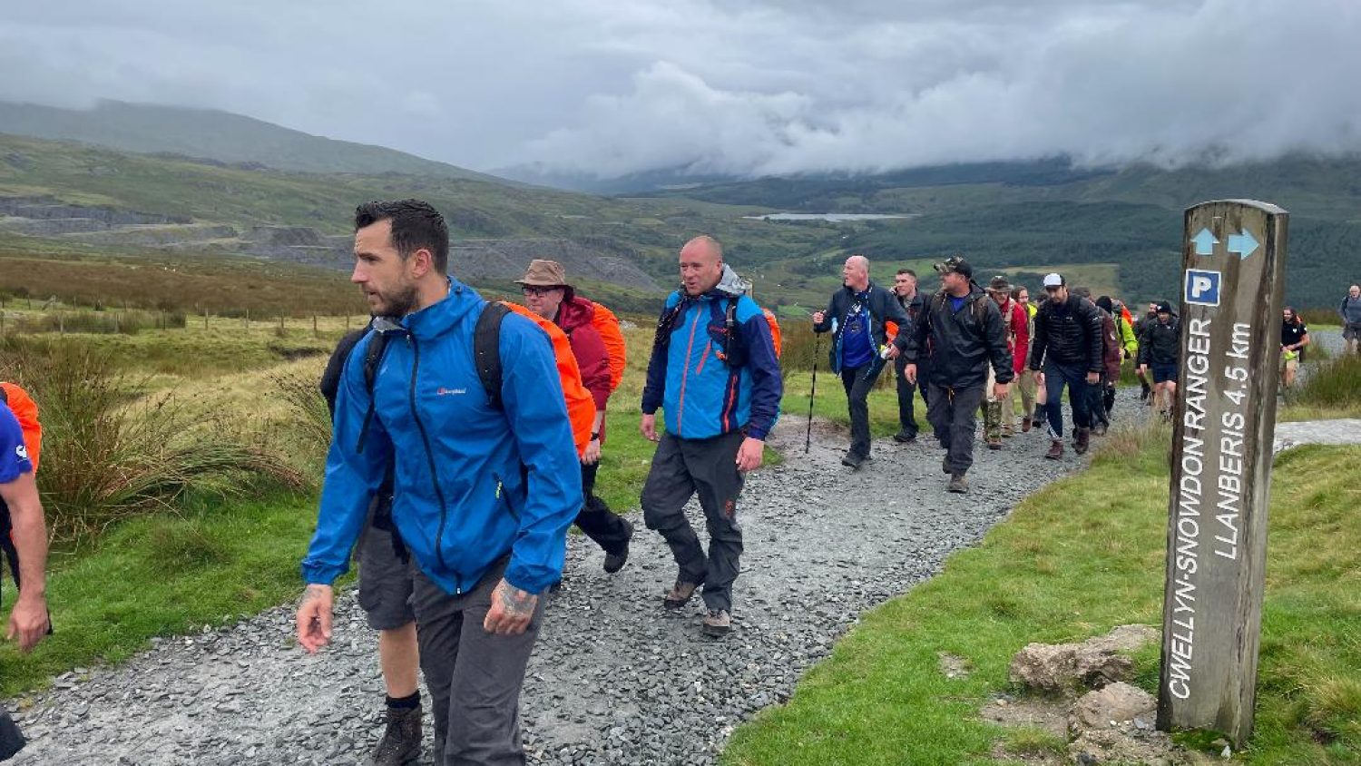 Group of men in waterproofs walking along a mountain path, as part of Strong Men UK grief support