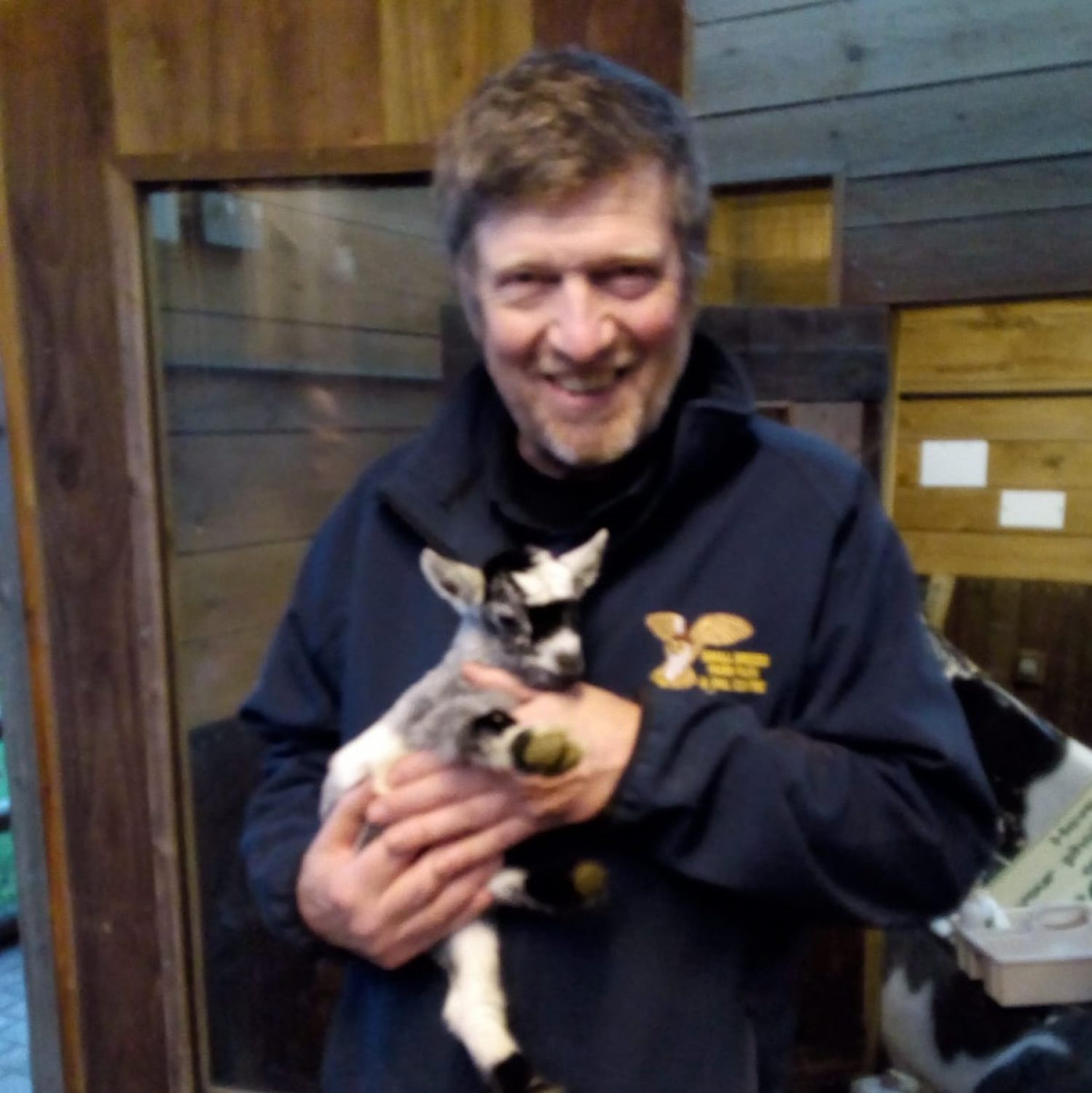 Meg's dad holding a baby goat, smiling