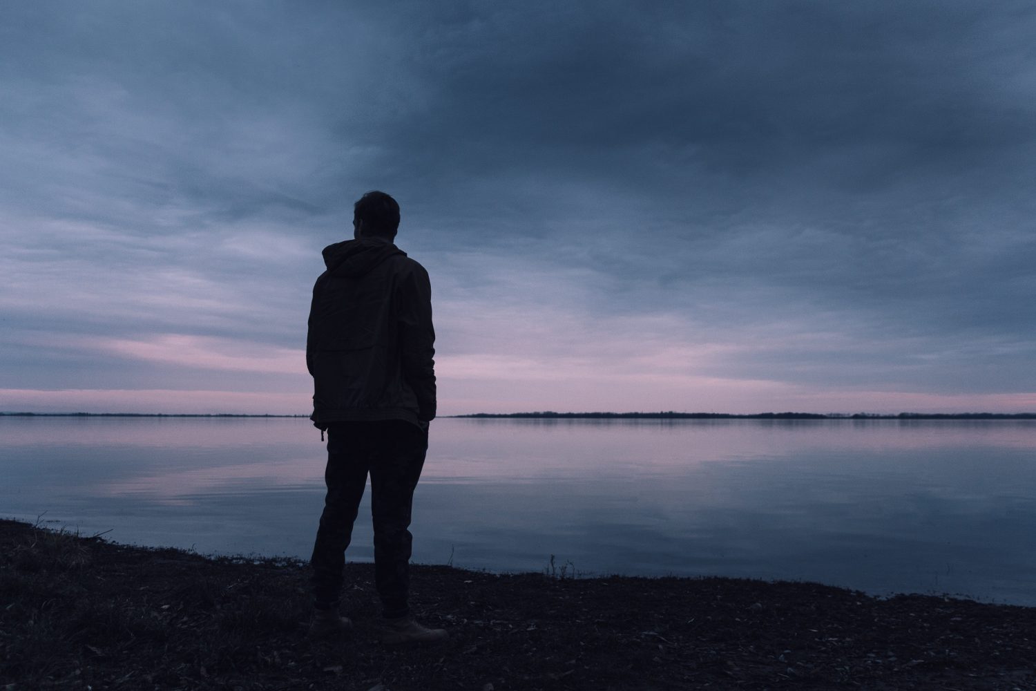 Person standing in front of a lake in twlight.