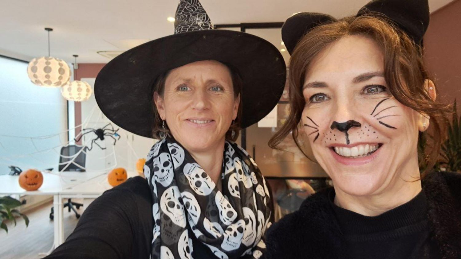 Two women, one with cat face paint, one with witches hat