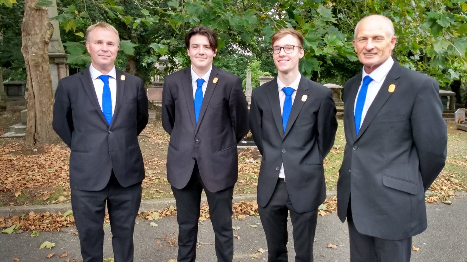 Four men in suits and blue ties as part of Poppy's team