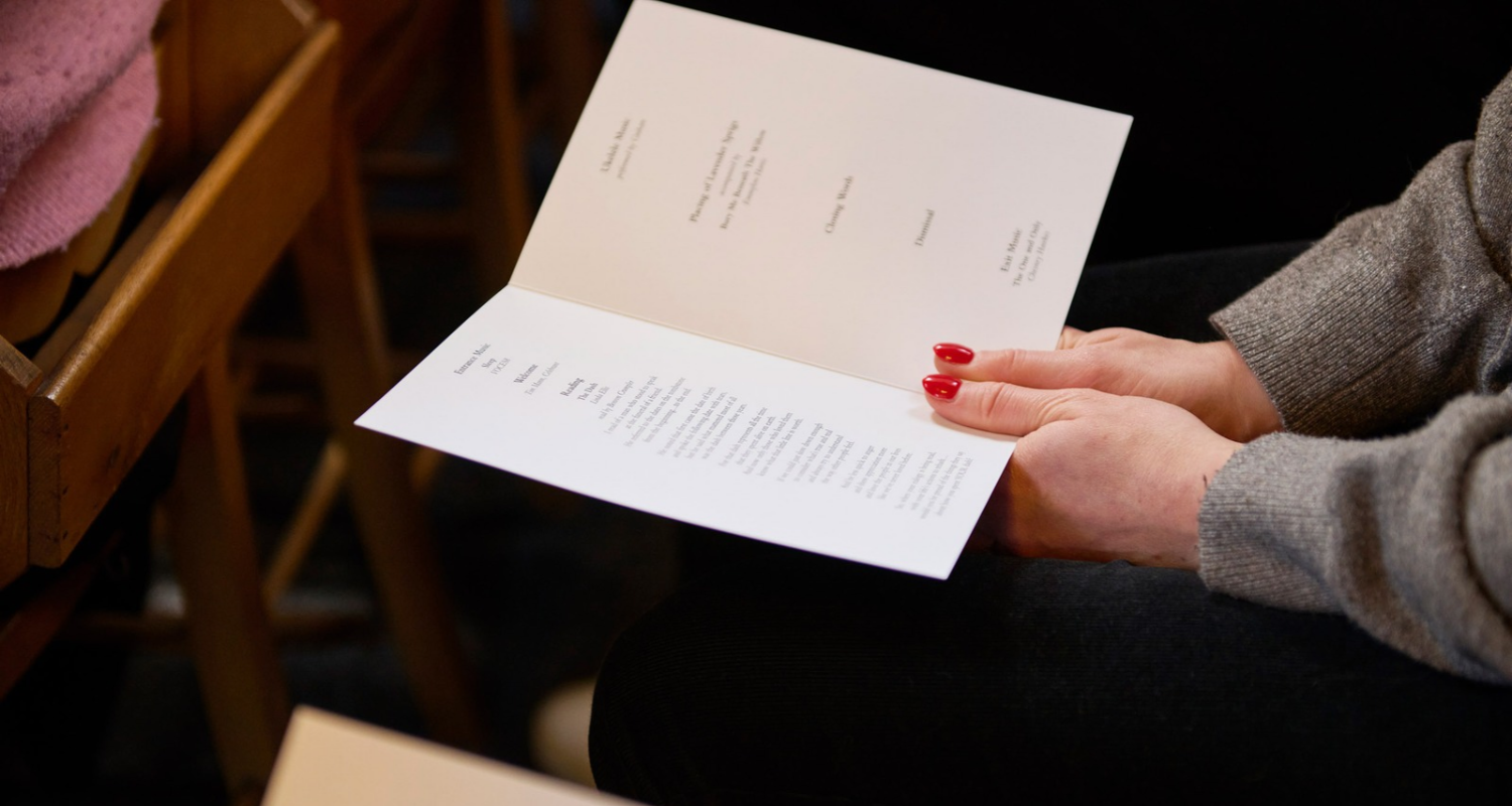 hands holding funeral order of service