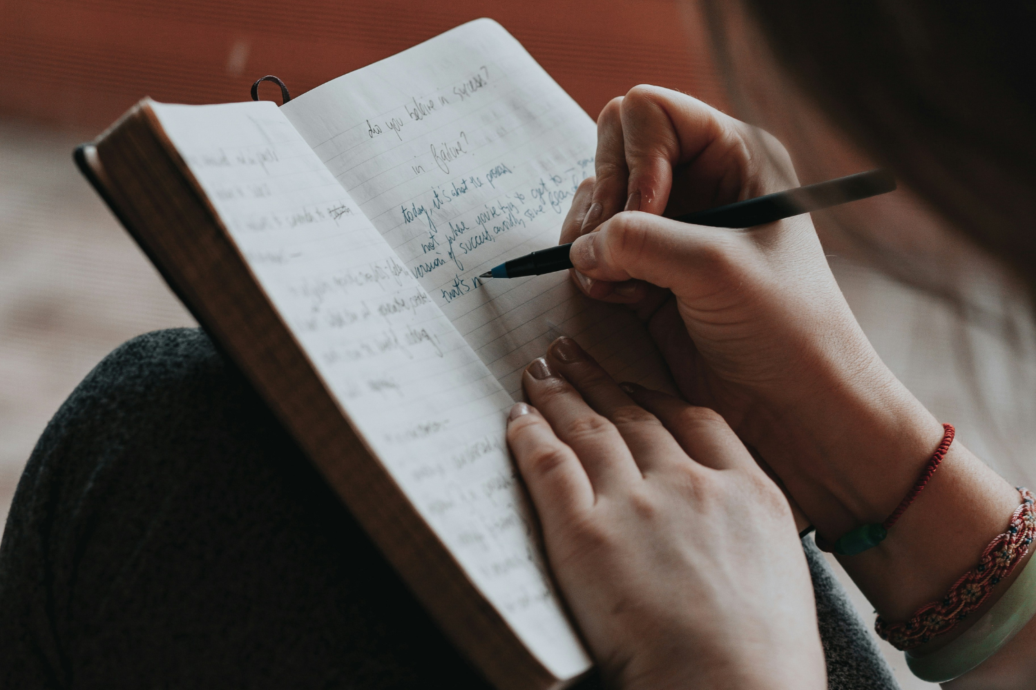a close up of hands writing in a journal