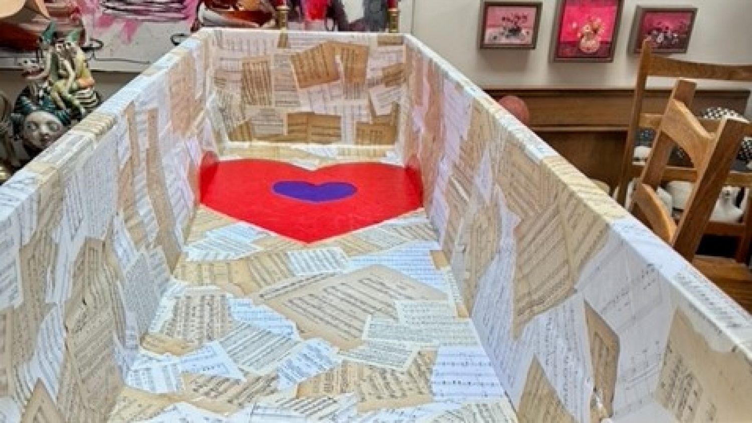 Cardboard coffin decorated with sheet music and red painted heart