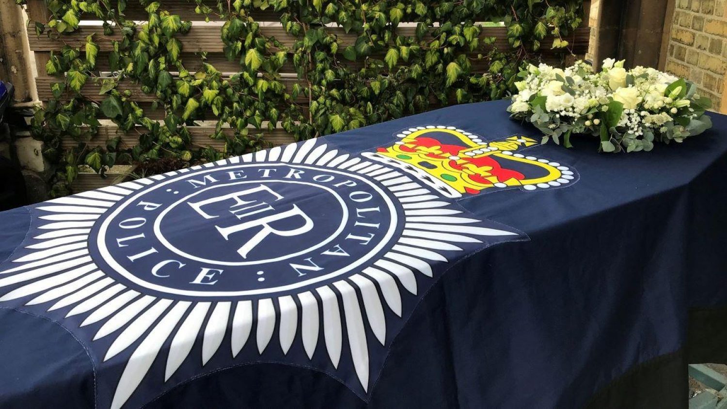 Cardboard coffin covered with Met Police flag