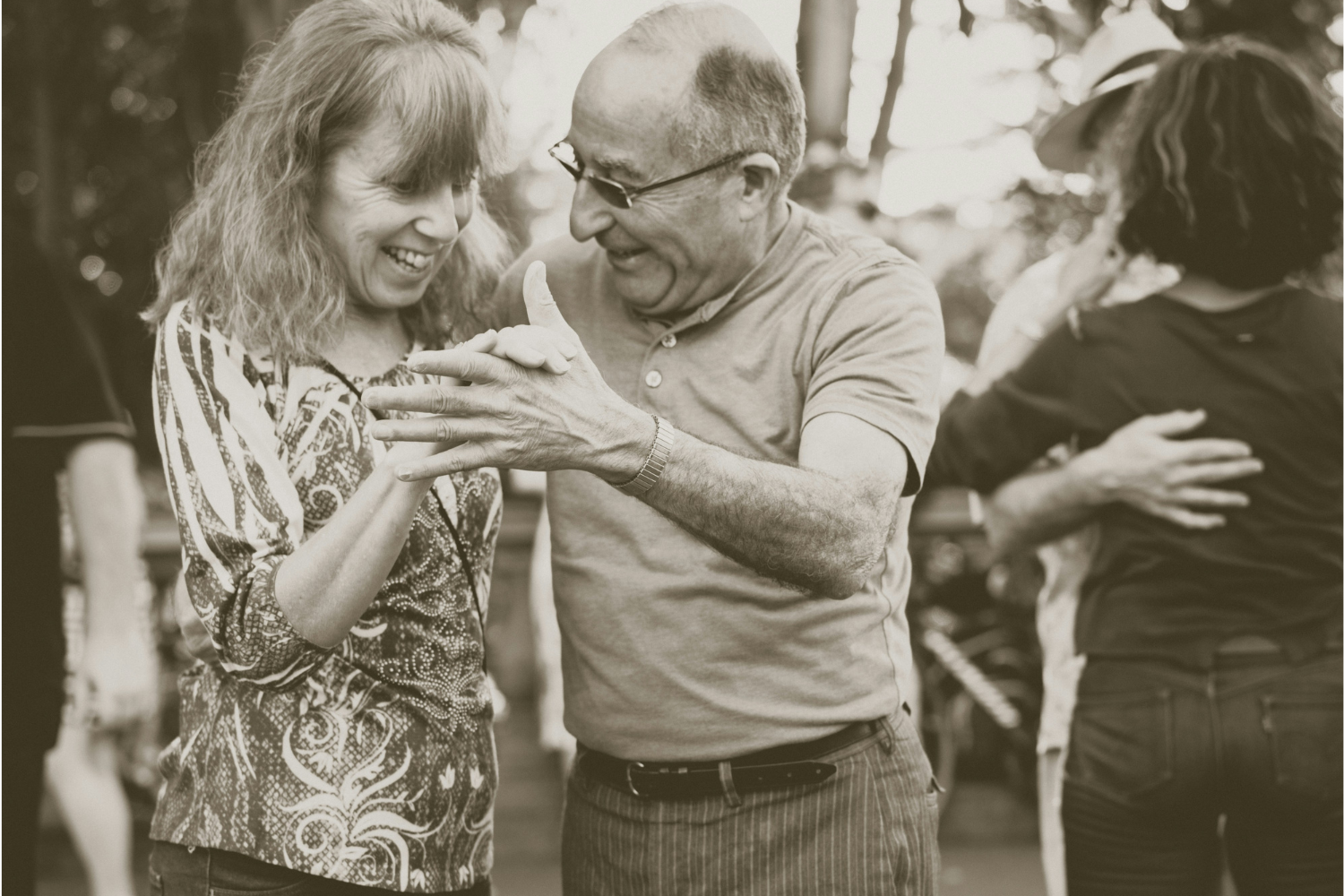 two middle aged people smiling and dancing together salsa