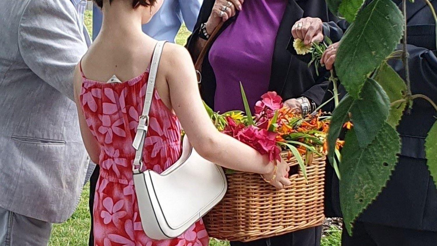 Young woman in pink dress distributing seasonal funeral flowers from a wicker basket