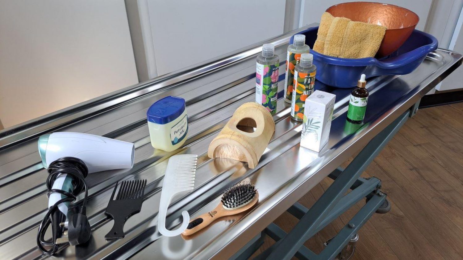 Hairbrushes, hairdrier, shampoos and other products on metal tray