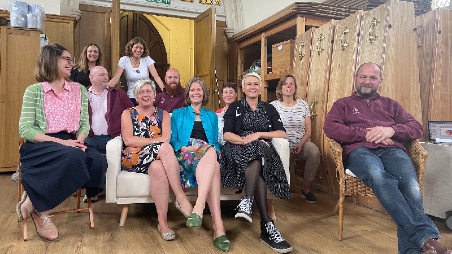 Poppy's team sitting in mortuary, all smiling, coffins in background