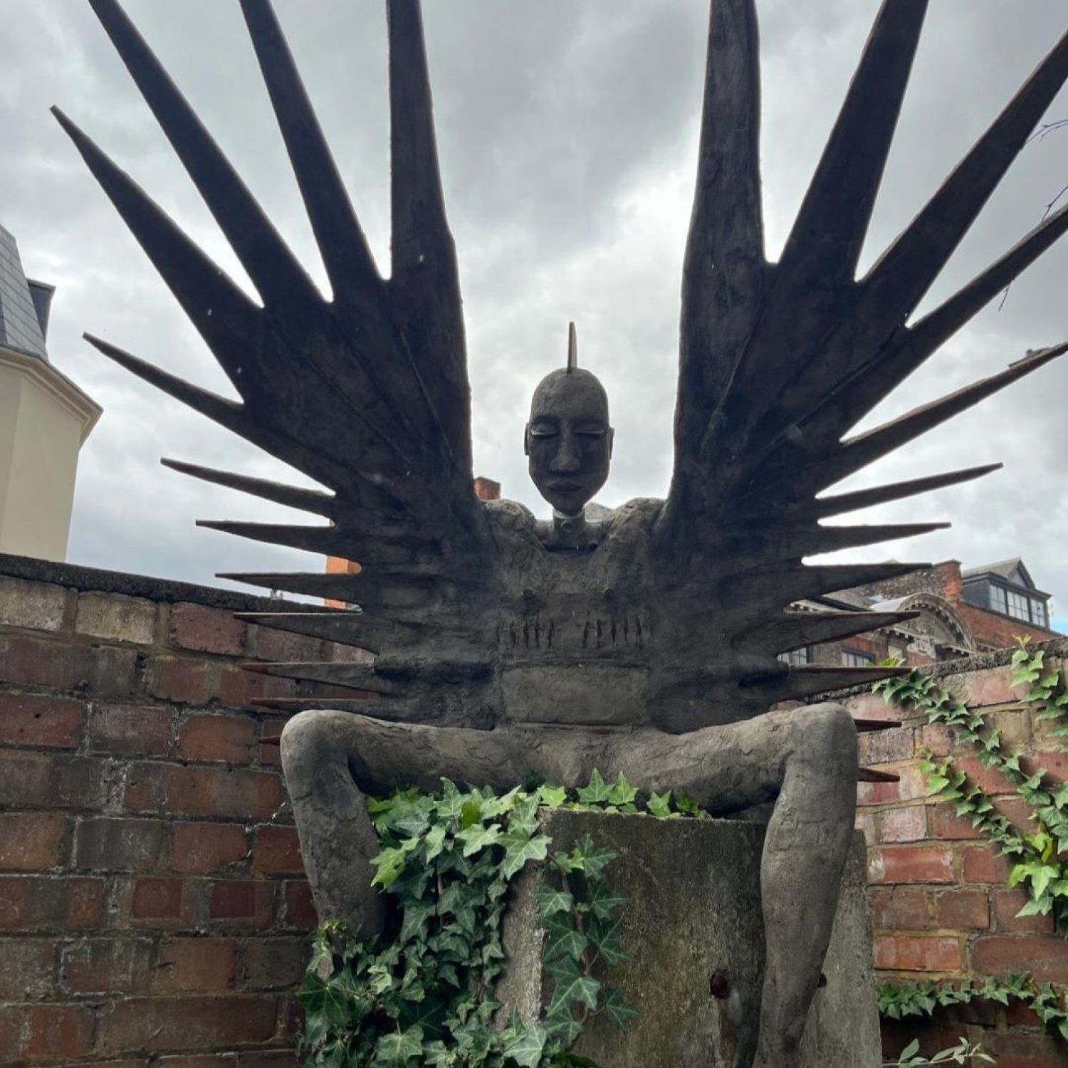 Metallic sculpture of a figure with spiky wings