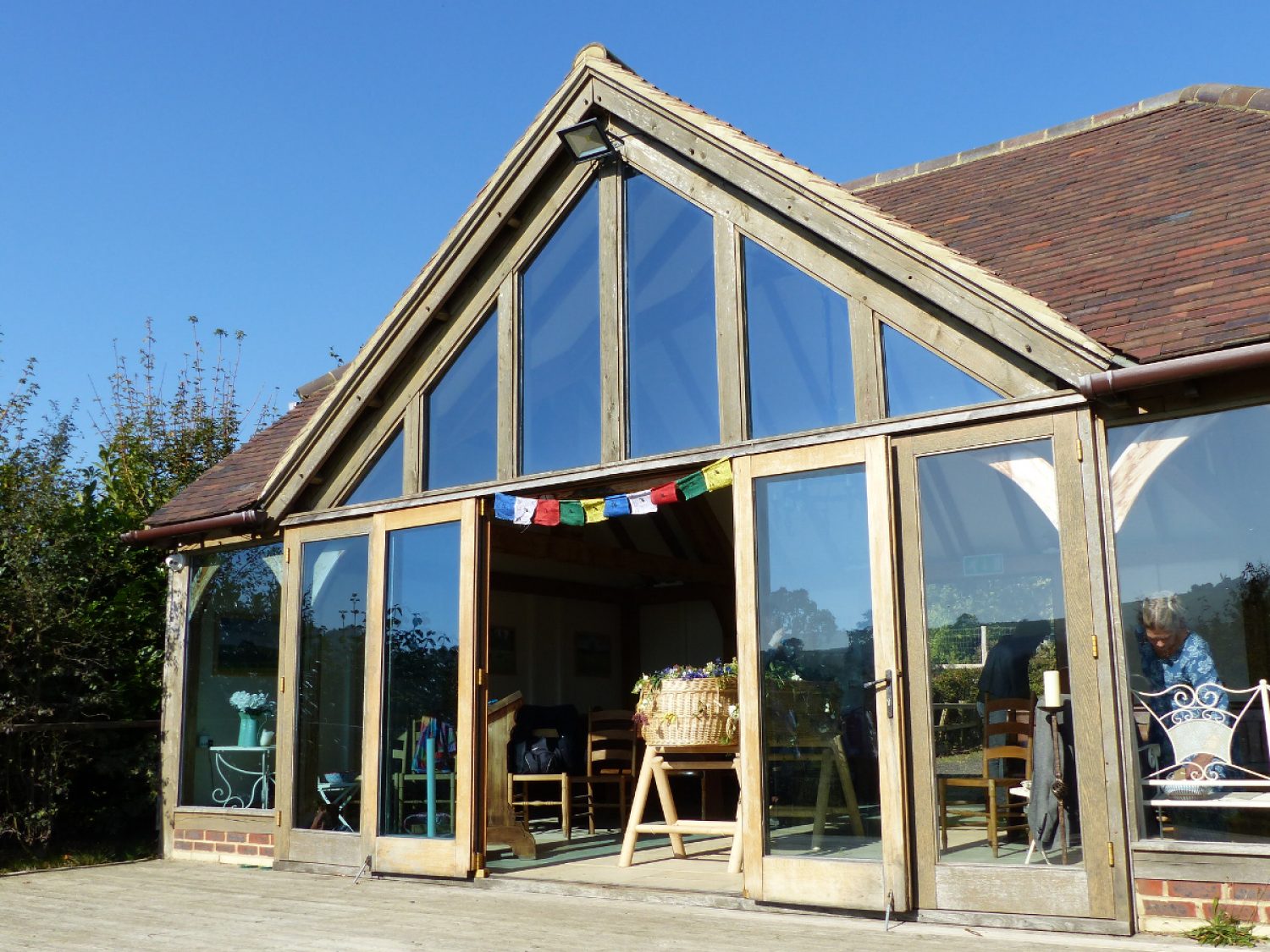 Alternative funeral venue, glass-fronted building with blue sky, bunting and willow coffin