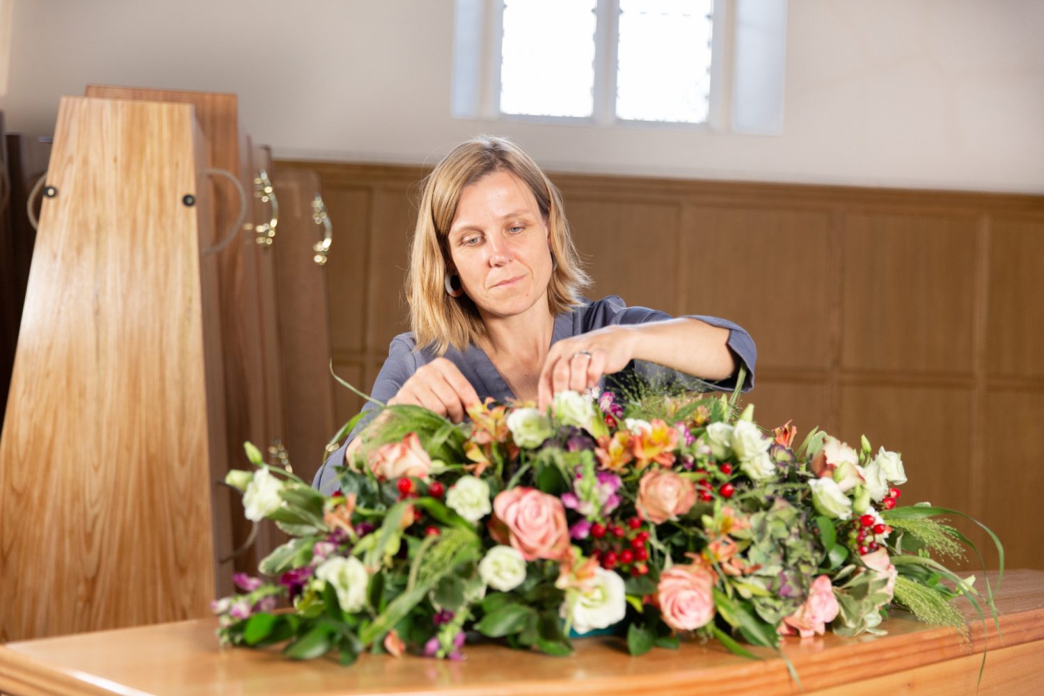 Arranging flowers on top of a coffin | Poppy's funerals | London funeral directors