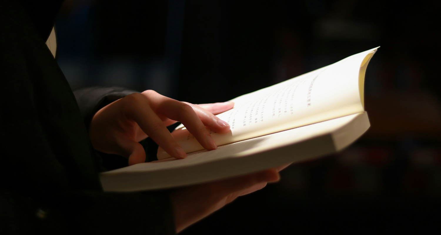hands holding an open book in a beam of sunlight